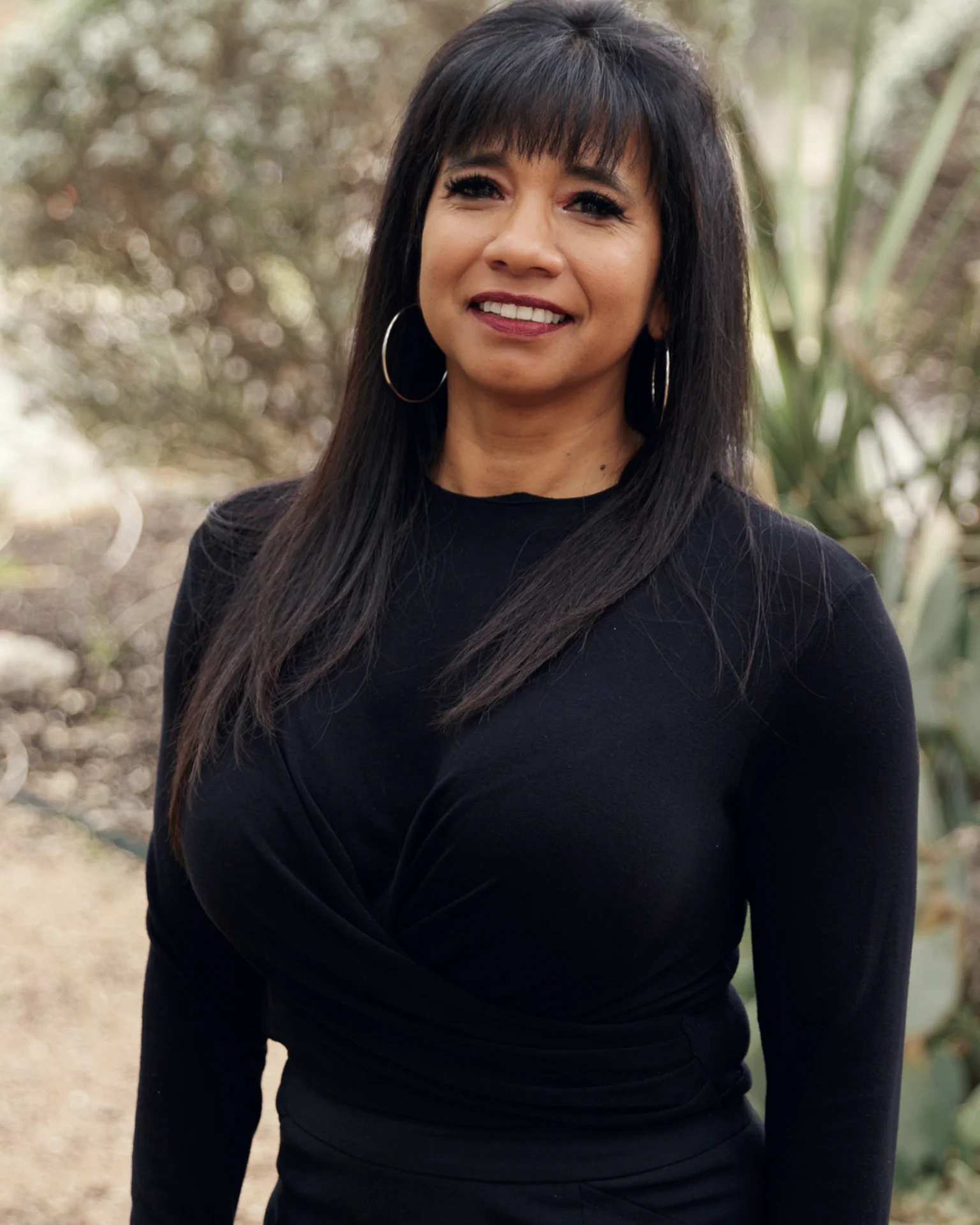 A woman in black shirt standing next to plants.