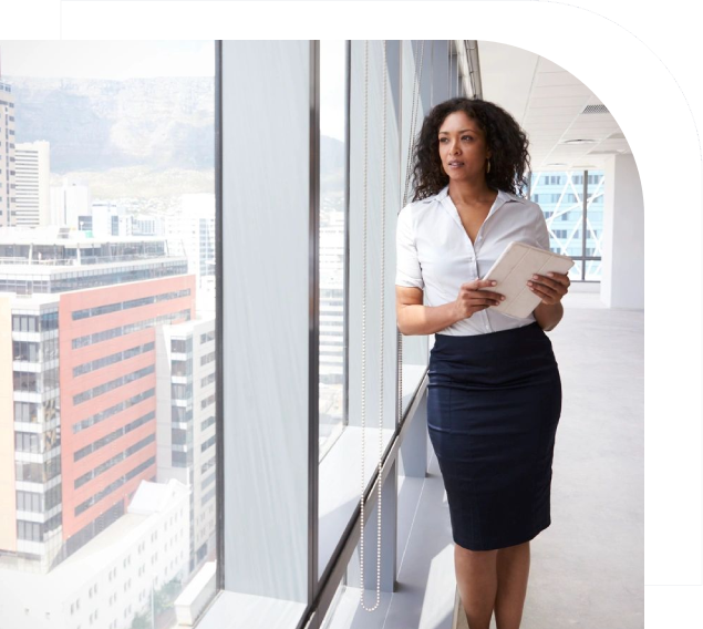 A woman standing in front of a window holding papers.